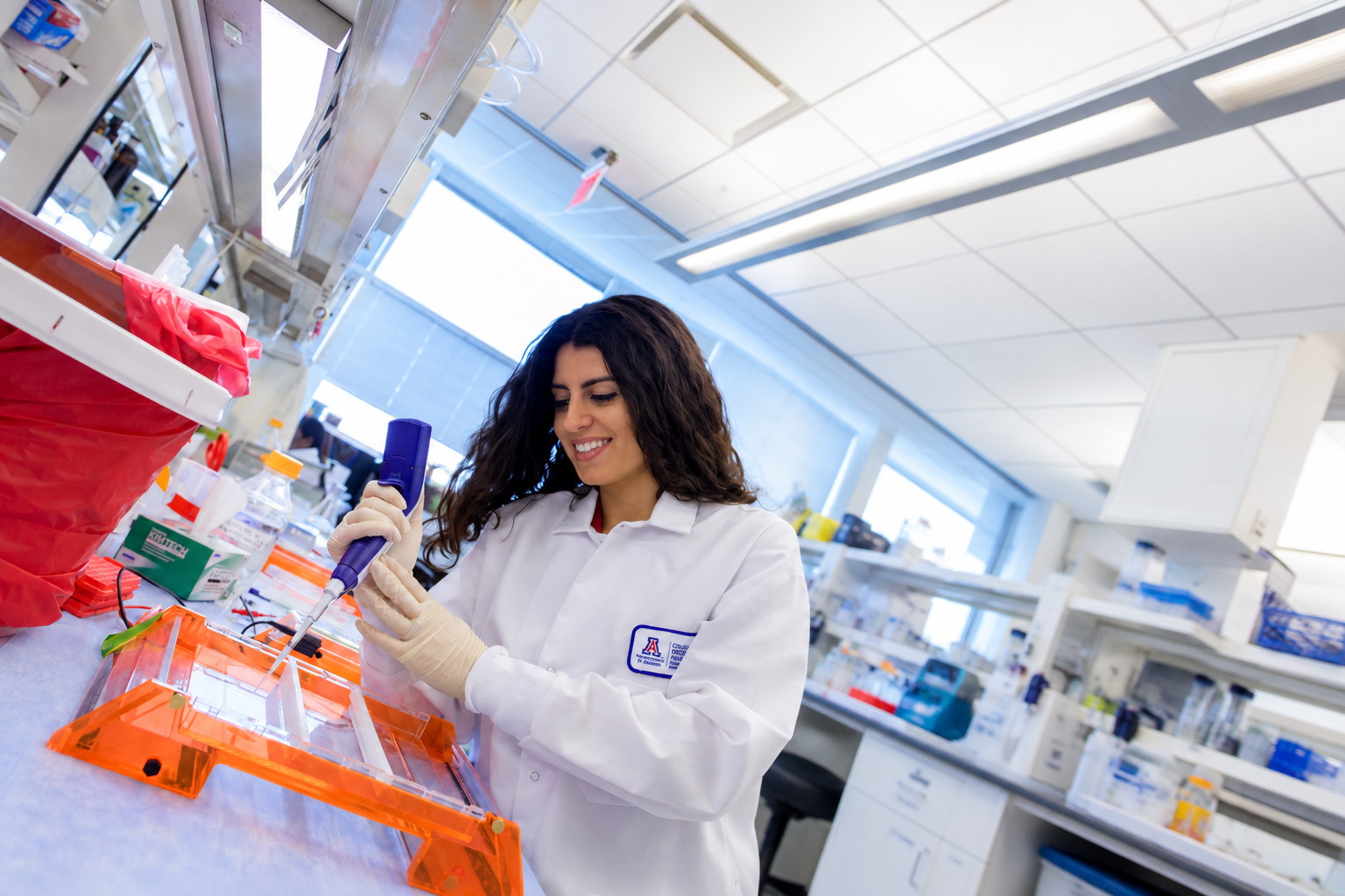 A lab member pipettes samples into a gel at the bench